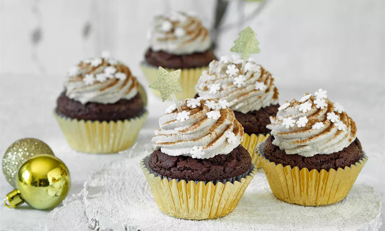 Vánoční perníkové cupcakes v zlatých košíčcích, tmavě hnědé těsto, světlý skořicový krém s cukrovými hvězdičkami a sněhovým zdobením